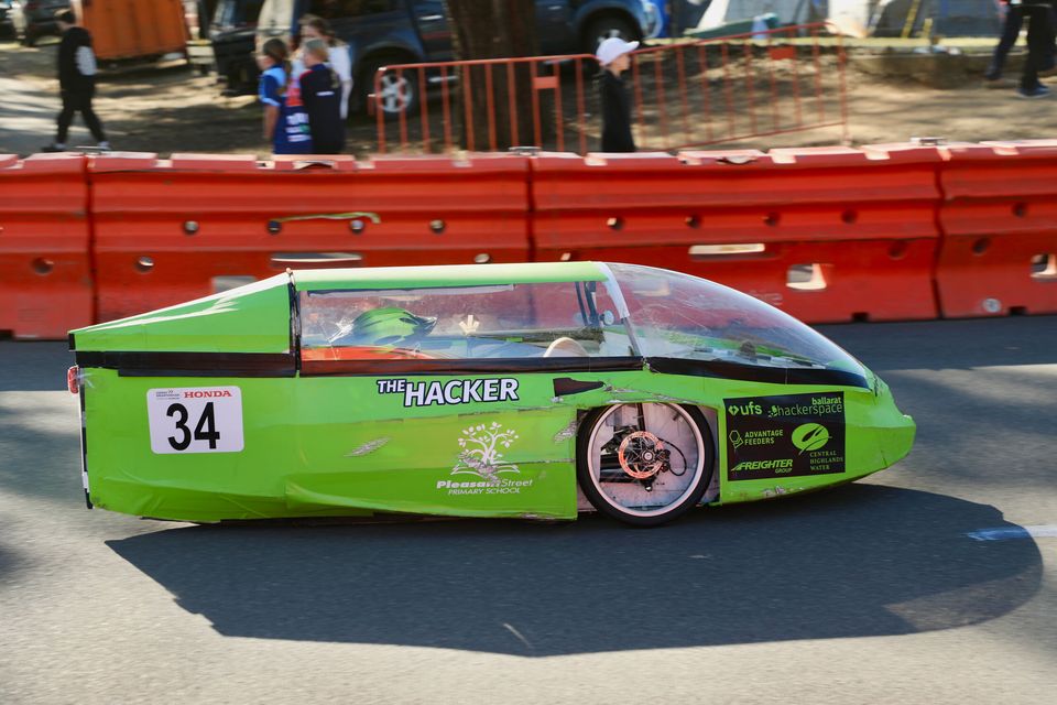 A green human-powered vehicle, number 34, on the race track
